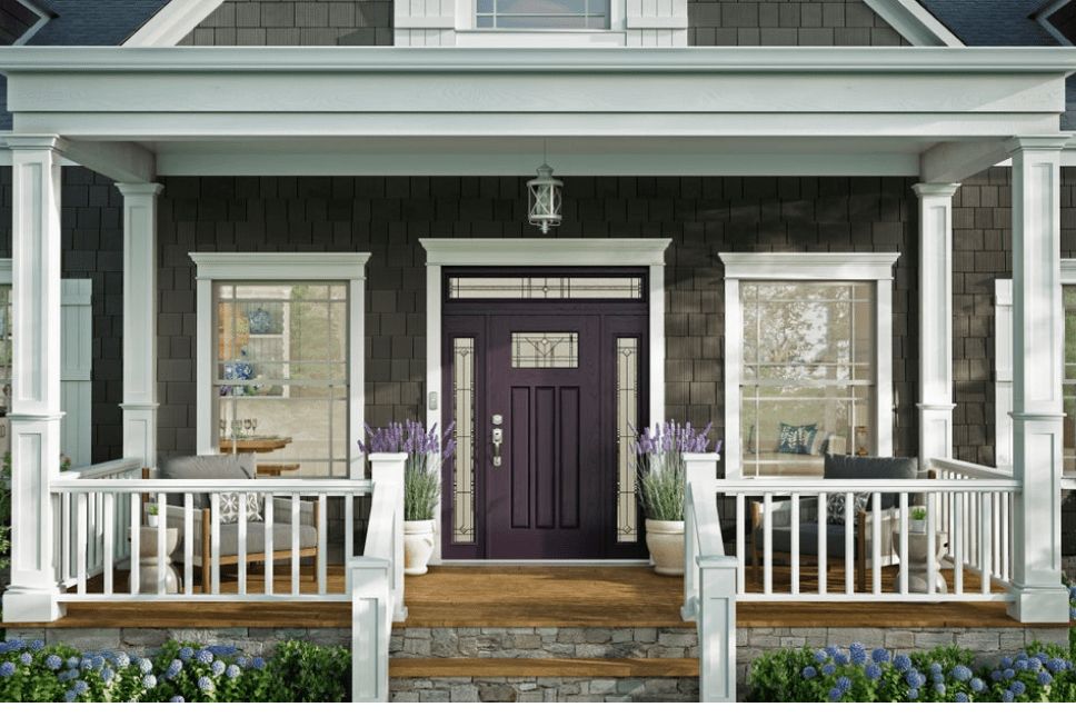 Front porch of a home with a dark red woodgrain door with glass sidelites and transom.