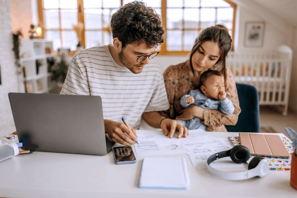 Man reviewing financial documents next to a woman with an infant.
