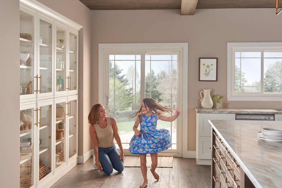 Sliding patio door behind a mother and daughter inside the home’s kitchen.